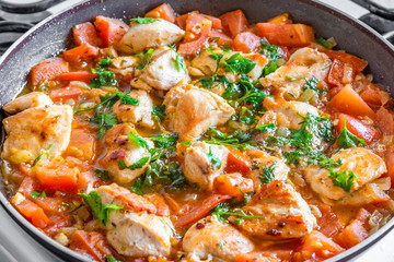 Chicken cacciatore is cooked in a frying pan, chicken stew with tomatoes and red pepper - top view