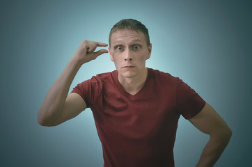 Surprised man is holding in hand a little copy space in front of his face isolated on blue background.