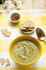Vegetable soup with broccoli, served with crackers, linseed oil and seeds.