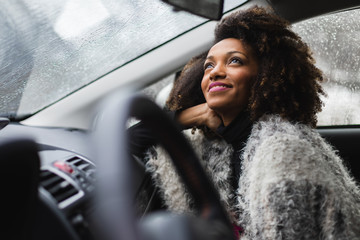 Relaxed woman looking the rain fall from inside a car during winter roadtrip.