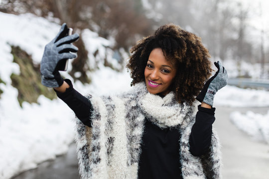 Cheerful woman taking selfie photo with smartphone in winter.