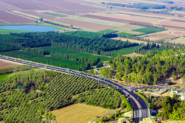 The road to Nazareth. Cars are driving along the highway. View from a height. Fields, forest, pond. Israel. Holy Land.