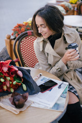 Fototapeta premium Young beautiful woman drinking coffee in a street cafe