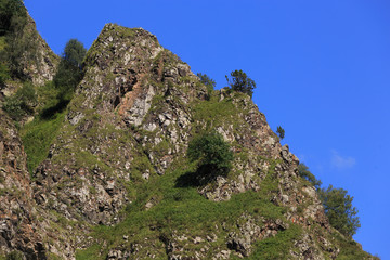 Stone ledge of a rocky ridge against the blue sky. Caucasian mountain range in Russia.