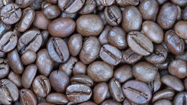 Fried coffee beans background, close up, rotation loopable 4k top view. Food  background. Gastronomy concept, organic food. Macro coffee beans