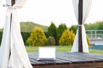 Laptop with black screen stands on wooden veranda