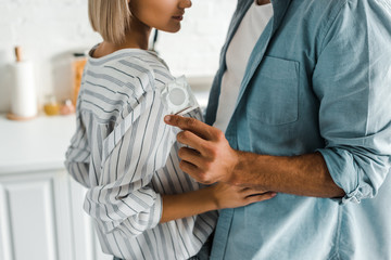 cropped image of boyfriend hugging girlfriend and holding condom in kitchen