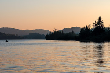 French landscape - Jura. View over the lake of Ilay in the Jura mountains (France) with fisherman in boat.