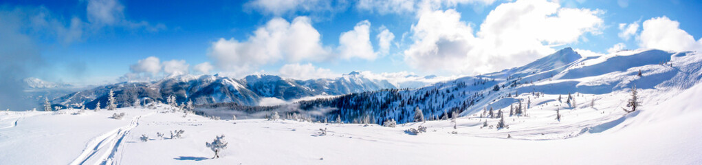 Fototapeta na wymiar Panorama view of a sunny and fresh snow covered mountaintop in Flachau, Austria