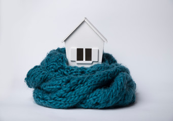 house in winter - heating system concept and cold snowy weather with model of a house wearing a...