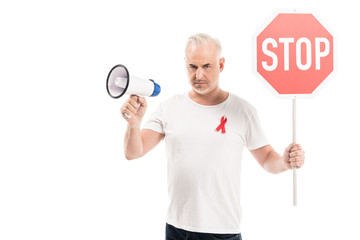 Fototapeta na wymiar angry mature man in blank white t-shirt with aids awareness red ribbon, stop road sign and megaphone isolated on white