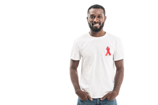 happy handsome man in blank white t-shirt with aids awareness red ribbon looking at camera isolated on white