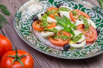 Fresh italian caprese salad with mozzarella and tomatoes on dark plate