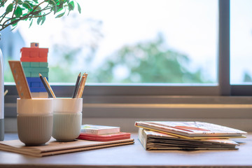 Children's bedroom with pencils and books on the table near the window.
