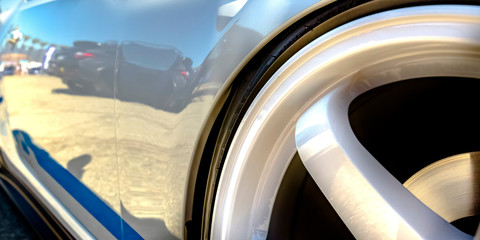 Wheel rim of a shiny white car with blue decal