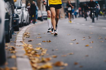 Marathon running race, people feet on autumn road. Runners run urban marathon in the the city....
