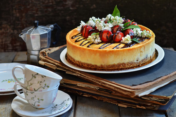 Cheesecake with Chocolate Icing. Strawberries on cheesecake. Lilac flowers on cheese cake