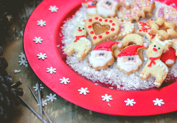 Royal icing decorated christmas cookies on red festive plate with snowflakes