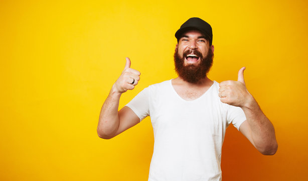 Cheerful young bearded man showing thumbs up