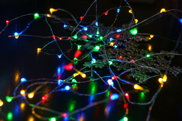 New year garland with little lamps on black background with snowflake