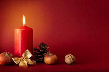 Christmas decoration with a burning candle on red background