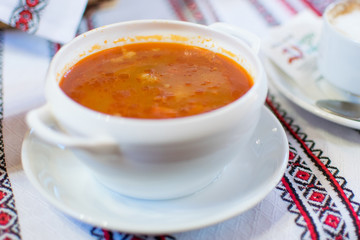 Ukrainian traditional borsch. Russian vegetarian red soup in white bowl on red wooden background.