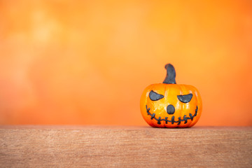 Scary Halloween pumpkin on wooden floor over blurred orange background, Halloween decoration and card concept