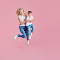 Positive young mother with a young son. Beautiful blonde with her baby boy jumping
