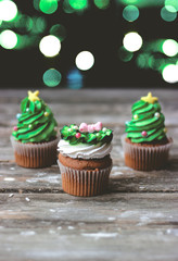 Vanilla cupcakes with christmas decoration, on dark background with colorful christmas lights