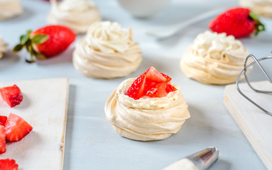 Strawberry pavlova cake nests, meringue decoration on a culinary table