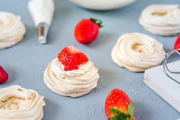 Strawberry pavlova cake nests, meringue decoration on a culinary table
