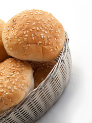 Una cesta plateada rellena de bollos de pan con sésamo visto cenitalmente 2