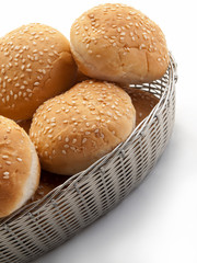 Una cesta plateada rellena de bollos de pan con sésamo visto cenitalmente