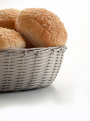 Una cesta plateada rellena de bollos de pan con sésamo visto frontalmente