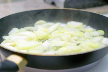 Onion is fried in a hot pan, steam enters, close-up