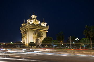 Fototapeta na wymiar Cars' light trails in front of the lit Patuxai (Patuxay), Victory Gate or Gate of Triumph, war monument in Vientiane, Laos, at dusk.