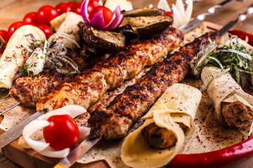 Kebab on skewers on a wooden tray with cherry tomatoes and hot pepper