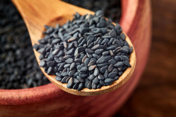 Fototapeta na wymiar Close up of black sesame seeds in wooden spoon