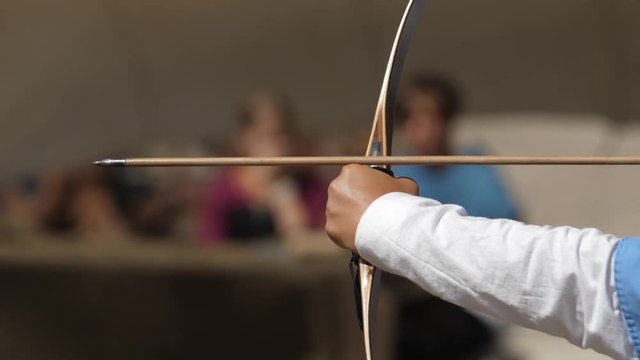 hand holds a bow and fires an arrow with a metal tip