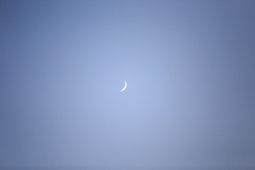 Sliver of new moon shines on beautiful blue night