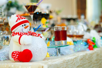 Snacks on the New Year's table, festive food, catering, reception, decor. Snowman in red clothes on the table.