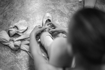 Young ballerina wearing pointe shoes. Close-up of a ballerina in the dance hall. Black and white photography.