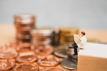 Miniature people, businessman reading newspaper on stack coins using as business and financial concept