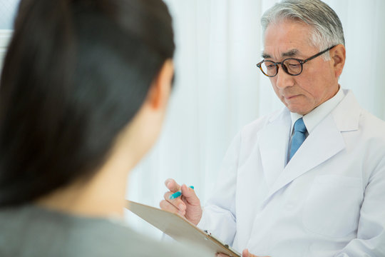 白衣を着た70代男性医師と患者