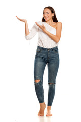 Barefoot young beautiful girl in jeans presenting something on white background