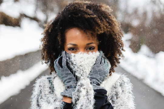 Afro hair young woman wearing wool scarf under the snow in winter