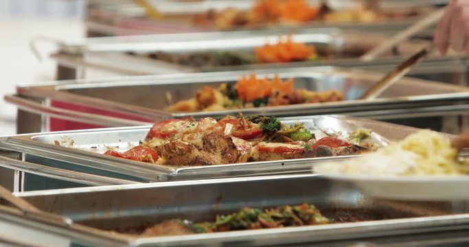 People group catering buffet food indoor in luxury restaurant with meat colorful fruits and vegetables. Close up. Banquet, lunch, bad nutrition, gluttony concept