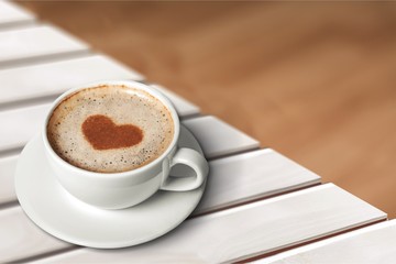 Coffee with heart shaped foam on wooden
