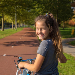 Happy kid rides a bike on a bike path.