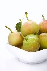Small pears, in a bowl, on a white background.